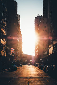 City street and buildings against sky during sunset