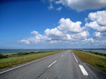 Road by landscape against blue sky