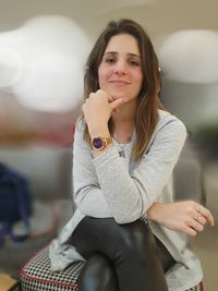 Portrait of smiling young woman sitting on chair at home