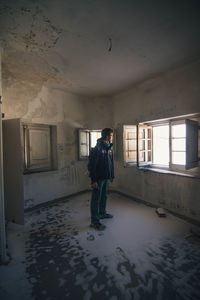 Man looking through window while standing in abandoned room