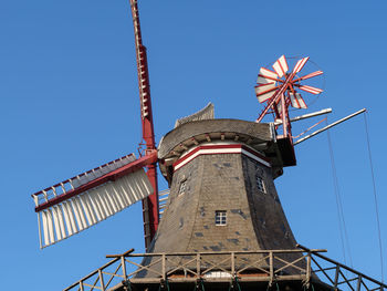 Low angle view of traditional windmill against clear blue sky