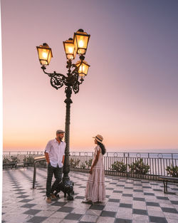 Illuminated street lights against sky during sunset