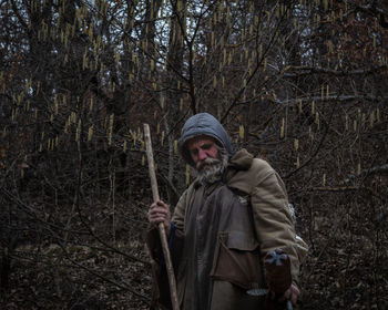 Man standing against bare trees in forest