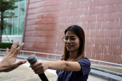 Smiling journalist giving microphone to cropped person