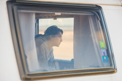 Woman in camper van seen through window