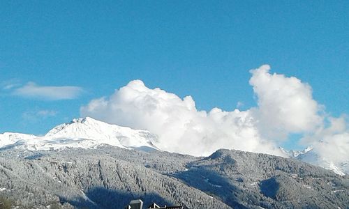 Low angle view of snowcapped mountains against blue sky