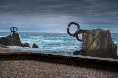 Metal structure on beach against sky