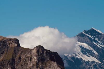 Low angle view of snowcapped mountains against blue sky