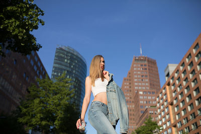 Low angle view of woman walking against buildings in city