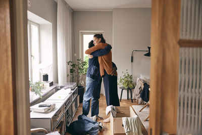 Side view of couple embracing each other while standing at home