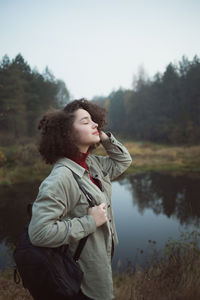 Side view of man looking away while standing by lake