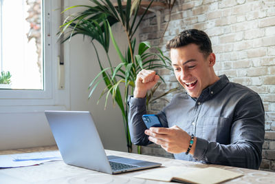 Young man using laptop while sitting on table