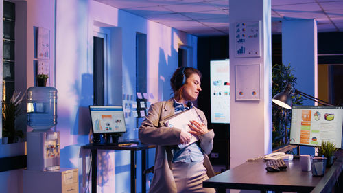 Portrait of young woman using mobile phone while standing in cafe