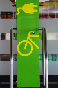 Close-up of green sign on railing in city