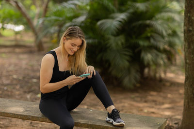 Woman using a smartphone at day time at a green park. mobile phone, technology, urban concept. 