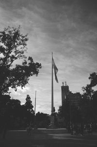 Group of people walking by trees in city against sky