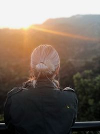 Rear view of woman looking at mountain against sky during sunset