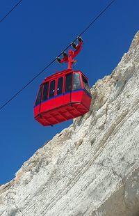 Low angle view of red flags hanging on mountain against clear sky