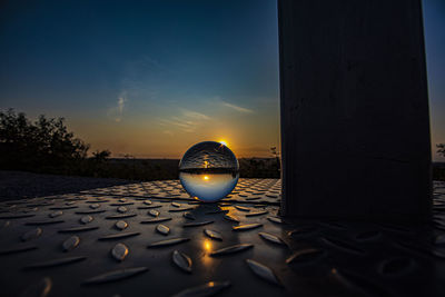 Close-up of crystal ball on water against sky during sunset