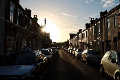 Cars on street in city against sky during sunset