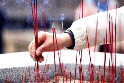 Cropped hand holding burning incense