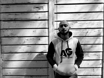 Portrait of bald young man standing against wall