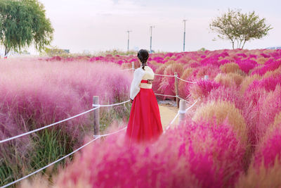 Rear view of woman standing on pink flowers