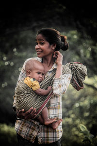 Smiling woman carrying son on textile