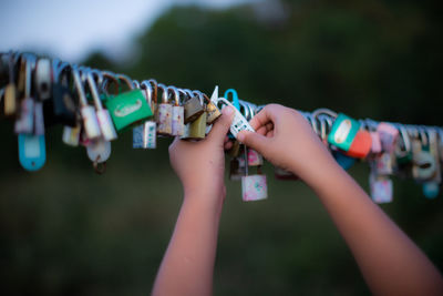 Close-up of hand putting padlock on cable outdoors