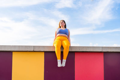 Low angle view of young woman standing against sky