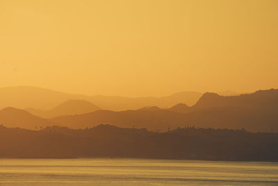 Scenic view of silhouette mountains against orange sky