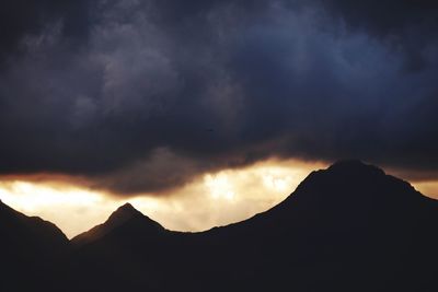 Scenic view of silhouette mountains against dramatic sky