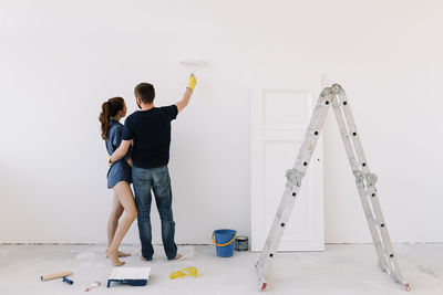 A young couple in love have moved into a new house and are making repairs painting white walls