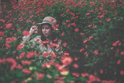 Portrait of woman with red flowers in field