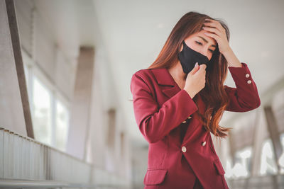 Young woman wearing mask standing against the wall