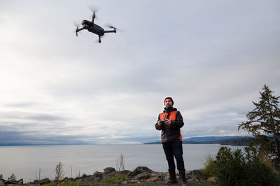 Low angle view of man with airplane flying against sky