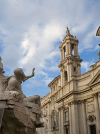 Low angle view of statue against historic building against sky