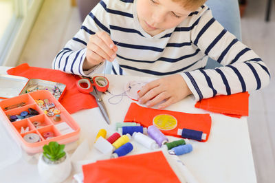 Caucasian boy who studies to sew with a needle and thread, additional education, leisure.