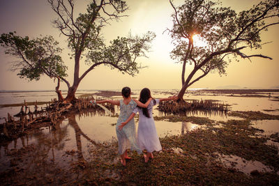 Friends enjoying at beach against sky