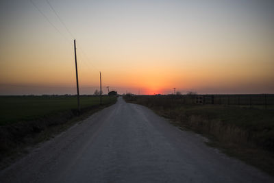 Road amidst trees against sky during sunset