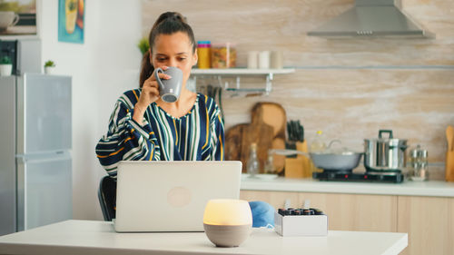 Portrait of young woman using laptop at table