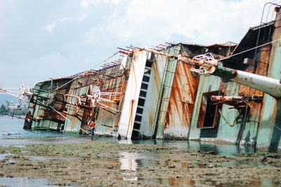 Abandoned building by sea against sky