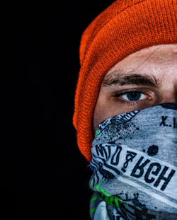 Close-up portrait of young man covering face with handkerchief against black background
