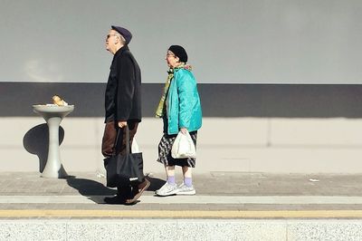 People walking with arms raised standing against sky