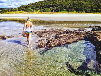 Full length of young woman on beach against sky