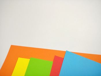 High angle view of multi colored paper against white background