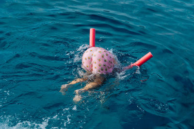 High angle funny photo of a person swimming with their butt up wearing avocado swim shorts.