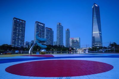 Modern sculpture by buildings against clear blue sky