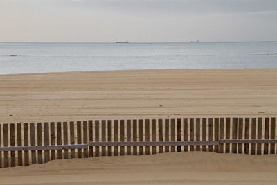 Wooden posts on beach against sky