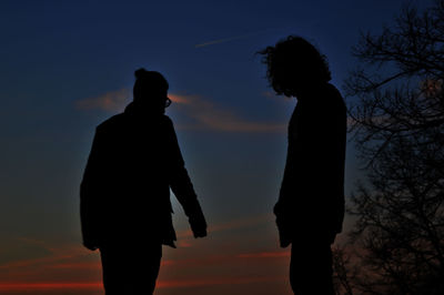 Silhouette people standing against sky at sunset